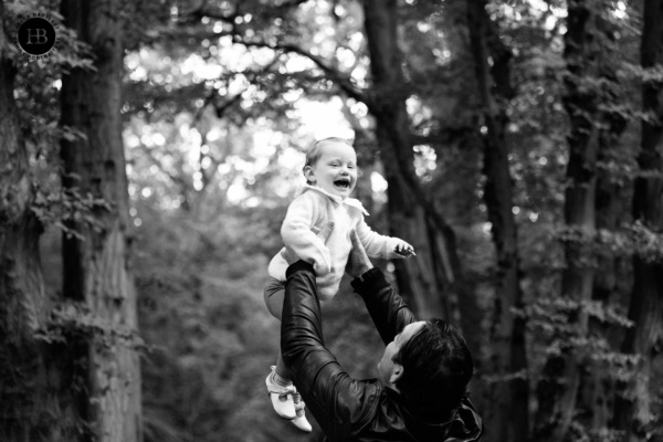 Father lifting baby into the air in a wooded setting by baby photographer n6 Helen Bartlett