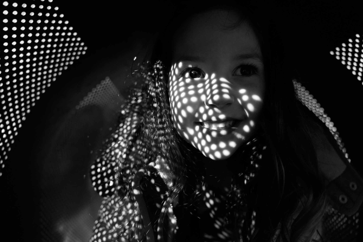 Child playing inside a tunnel with light and shadow patterns across her face