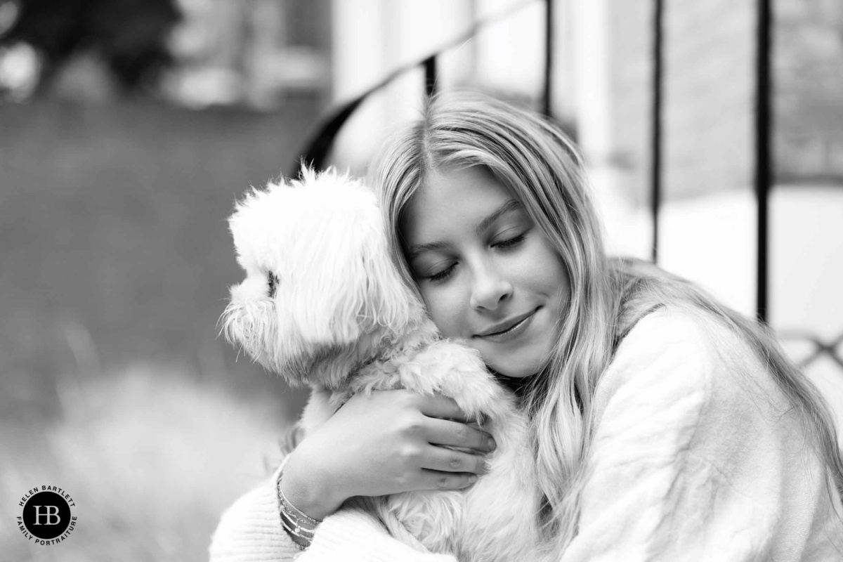 Teenage girl cuddling a small dog during a family photo shoot