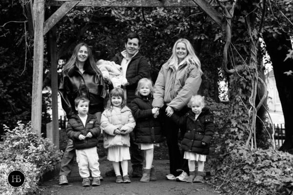 Family portrait with five children under five and parents standing together in a park