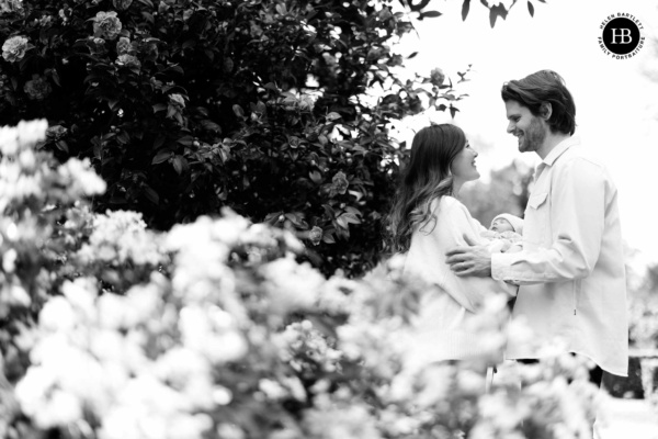 Parents holding newborn baby surrounded by flowers during outdoor newborn photography West London