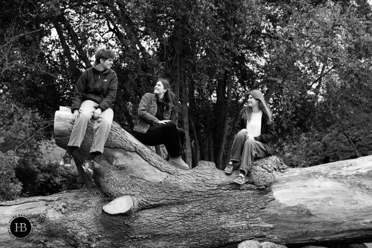 Teenagers sitting on fallen tree in park relaxed family photo shoot Title: Teenagers on Log Portrait