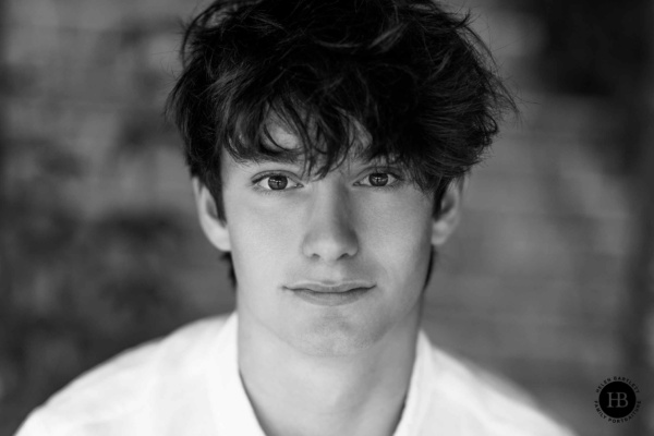 Close-up portrait of a relaxed teenage boy looking directly at camera, photographed by Helen Bartlett