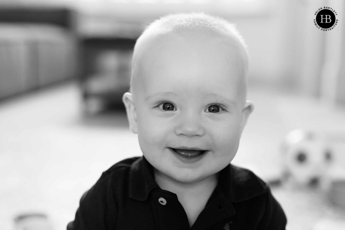 Portrait of a nine month old baby boy sitting on the floor of his living room during an at home family photo session in Fulham