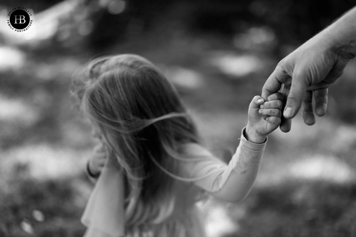 Black and white detail photograph of a young girl's hand holding her father's finger, outdoor family photography at Kew Gardens