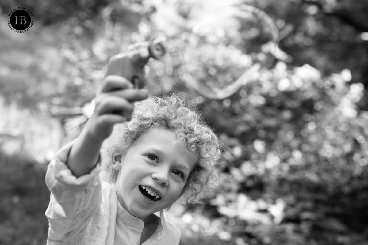 little boy plays with bubbles during a family photo shoot on Putney Commons