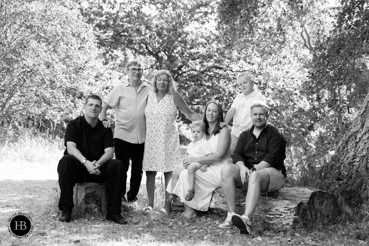 Three generation extended family group portrait seated and standing under trees in Kew