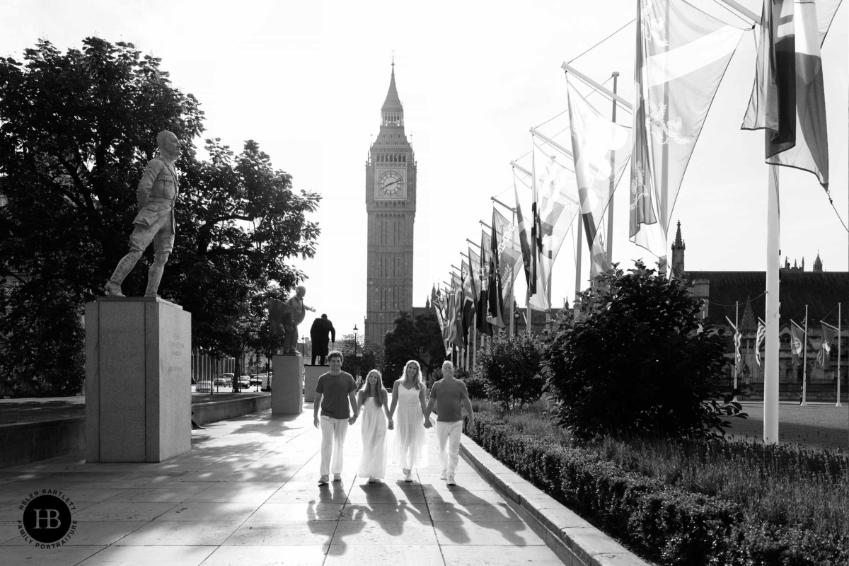 Family walking hand in hand near Westminster with Big Ben and long morning shadows