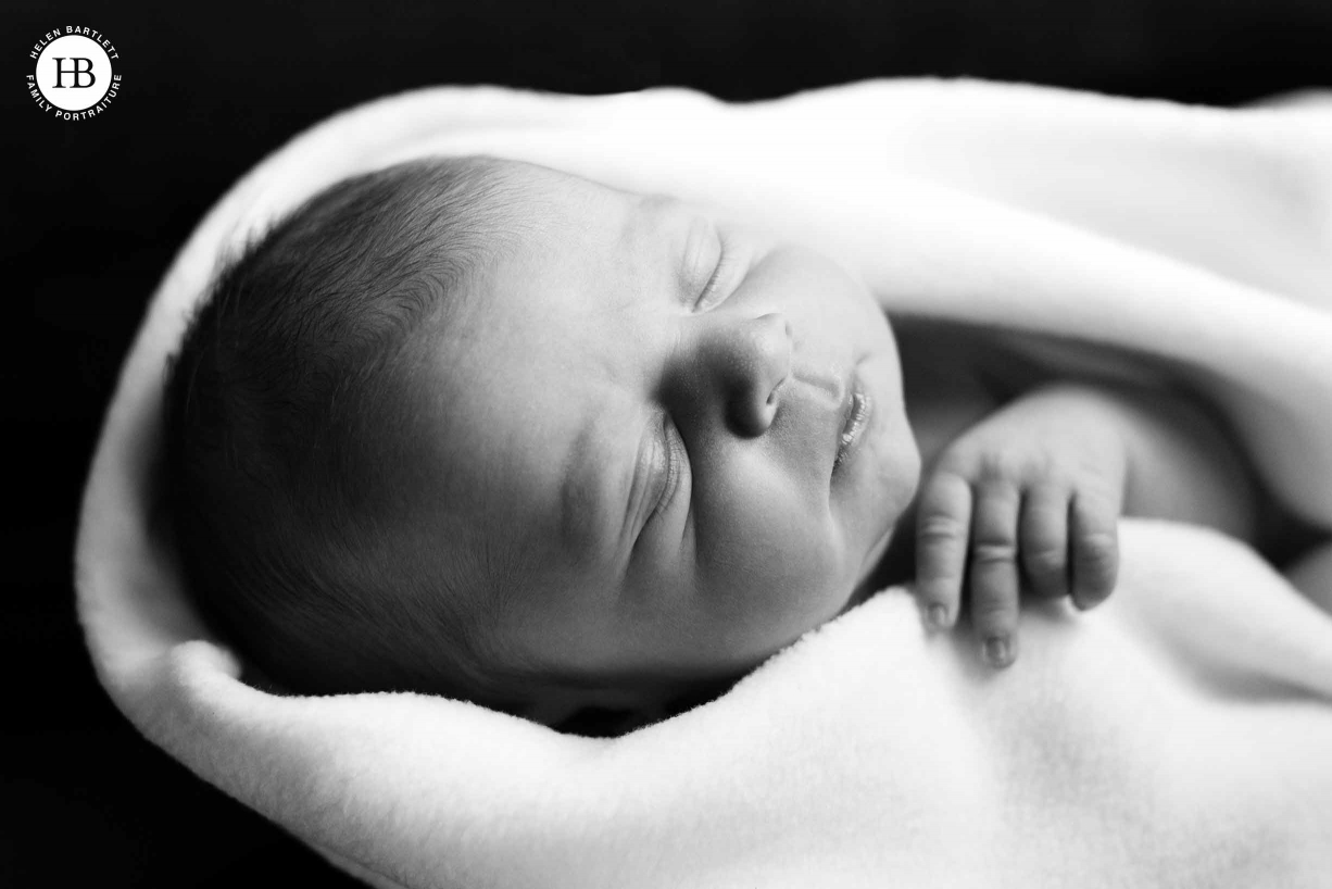 sleeping baby wrapped in blanket by newborn baby photographer in battersea