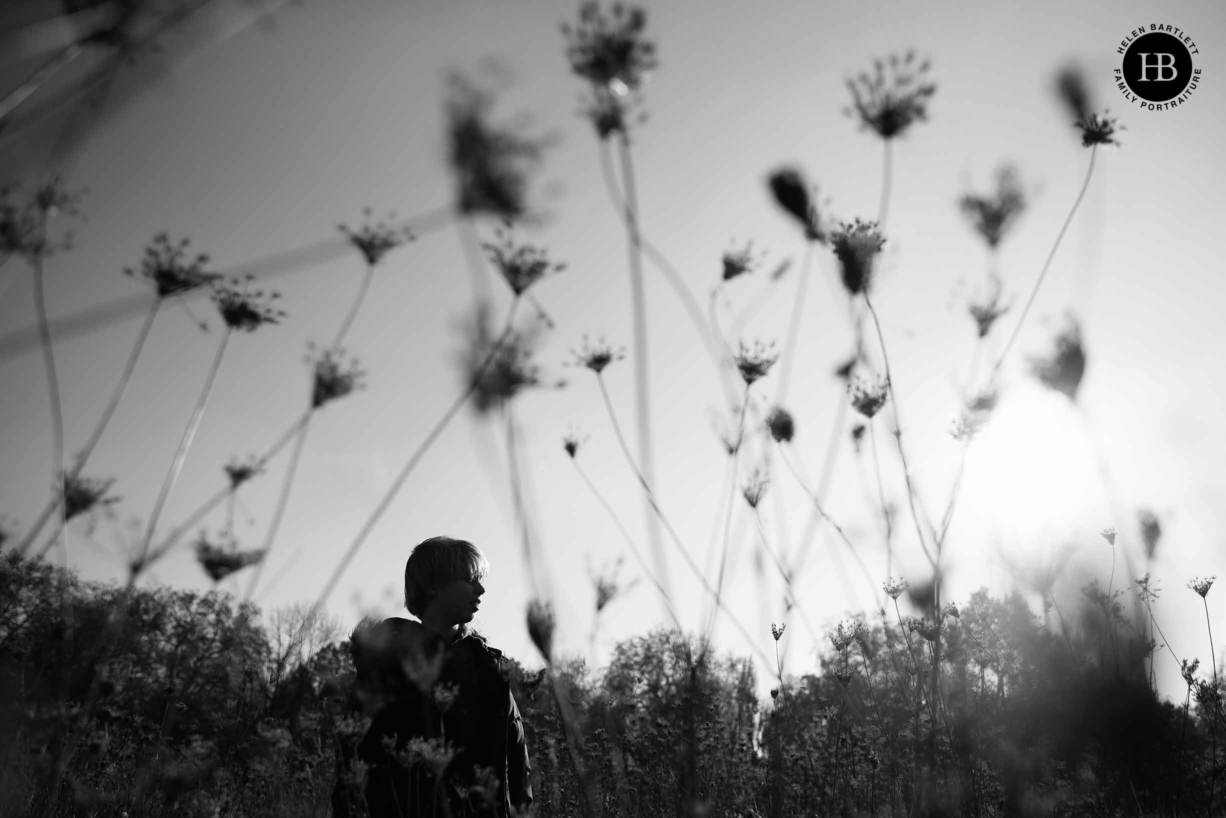 silhouette of boy among long grasses, dramatic black and white photograph