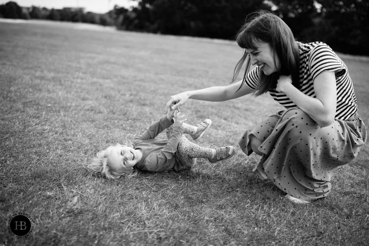 Mum tickles her daughter during a family photo shoot, both are laughing