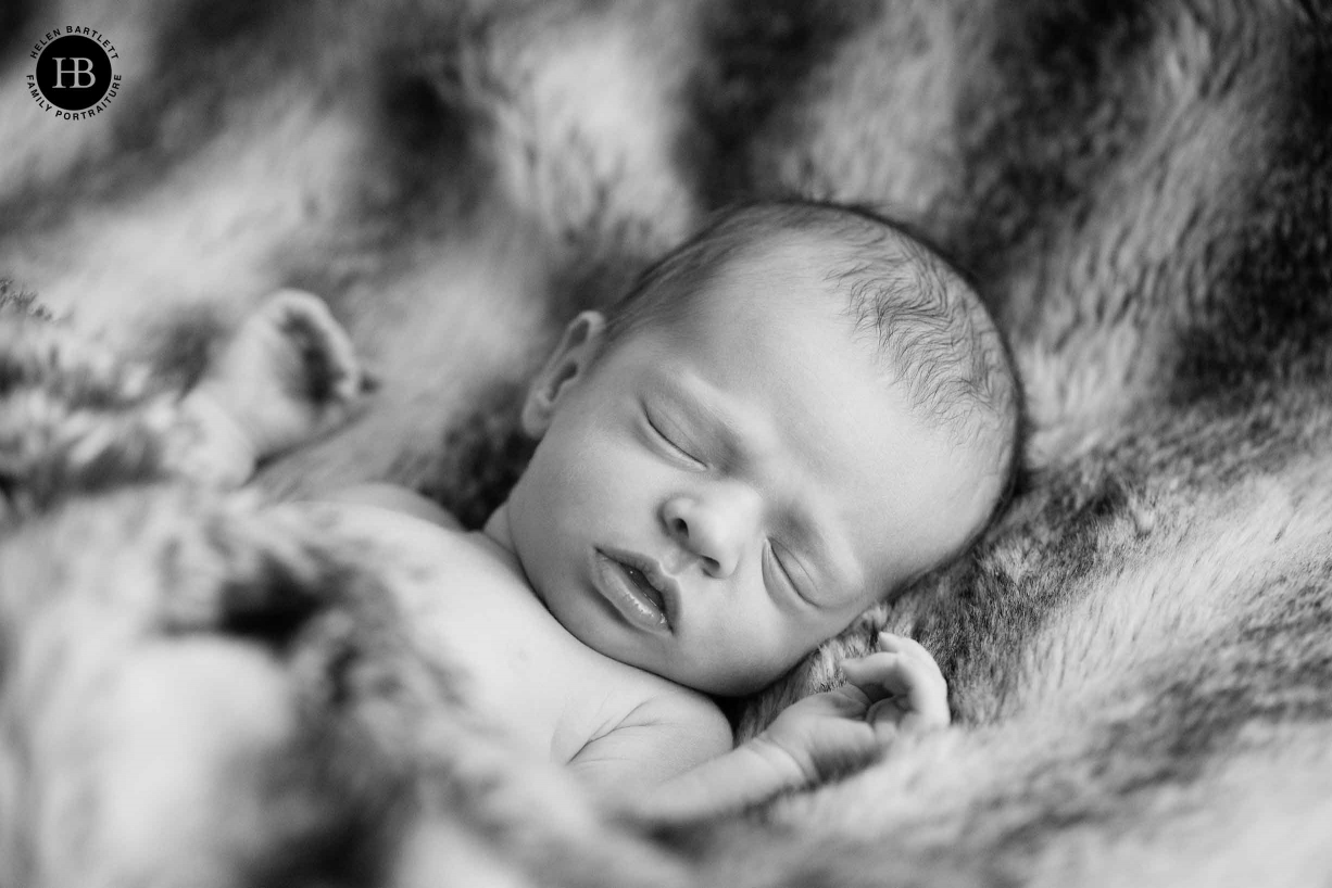 sleeping newborn baby girl wrapped in soft fur blanket