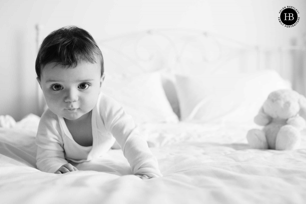 nine month old baby crawls on bed with a cuddly rabbit toy