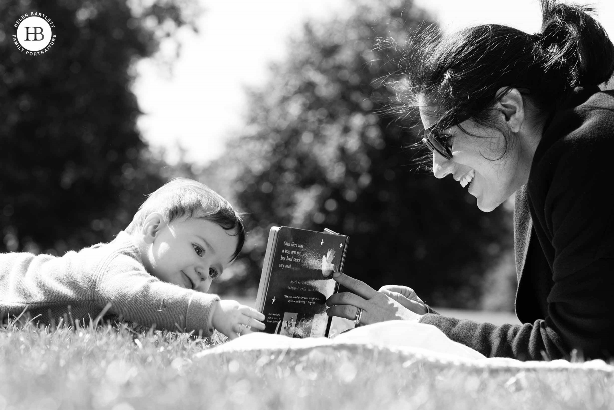 baby and mum read book in the park on summer day