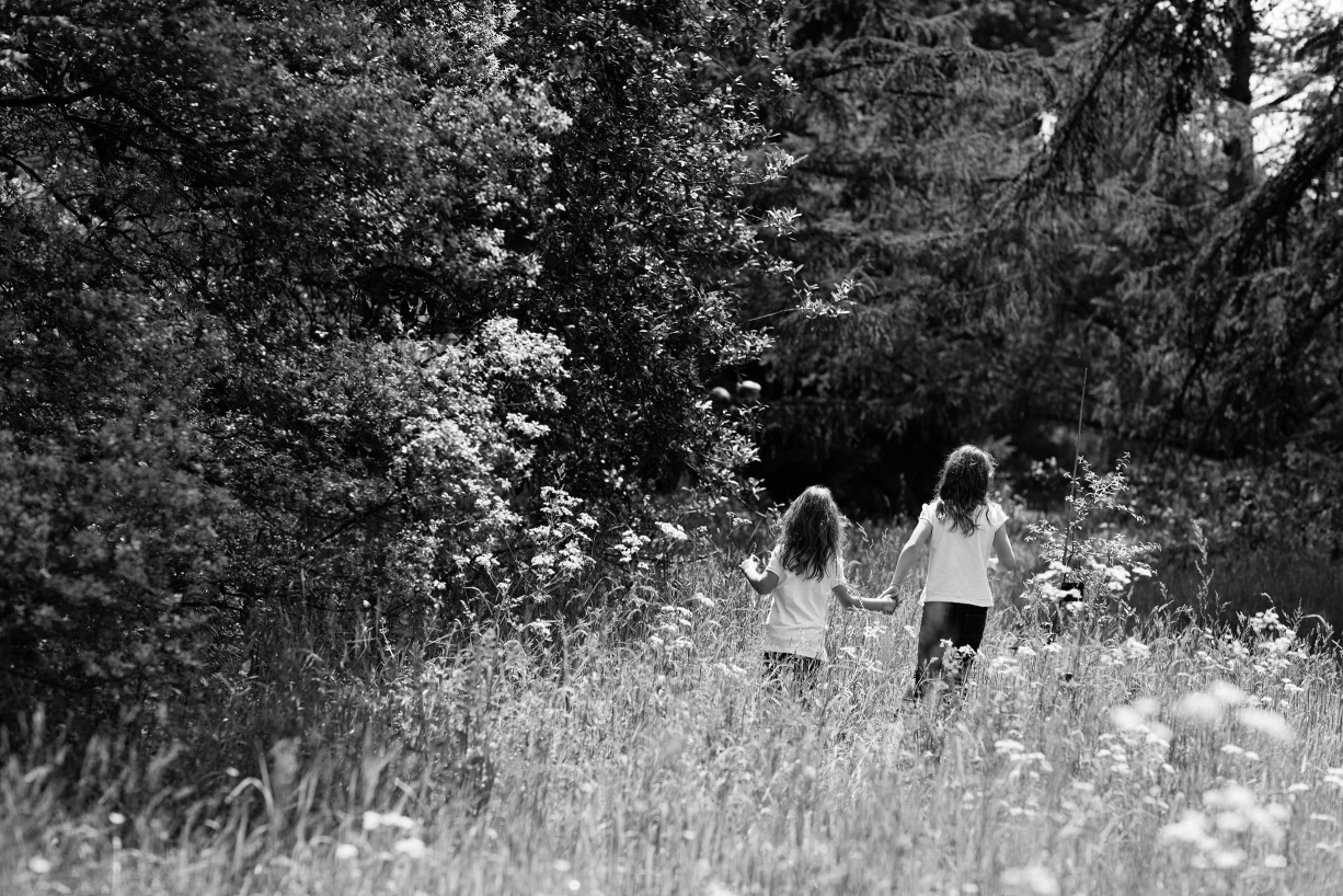 Sisters walk through the long grass during their family photograph session in Kew, west London