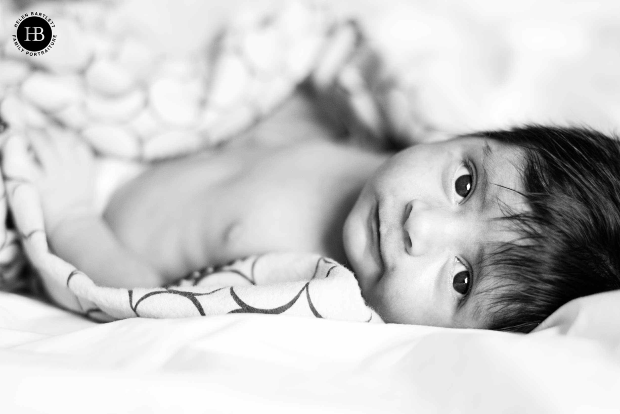 A wide-awake newborn baby during its lifestyle shoot at home. Read the complete guide to having newborn photos taken in your own home.