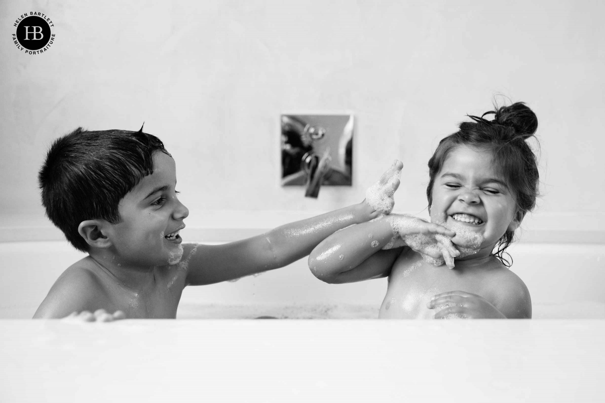 Siblings play in the bath during family photography in Wandsworth.