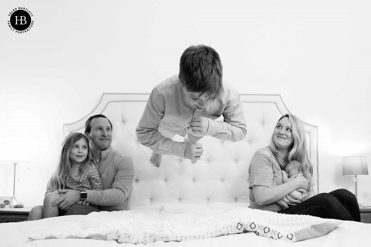 A skilled newborn photographer will charge more but the images will be worth it. Here a boy jumps on a bed and appears to levitate as family looks on