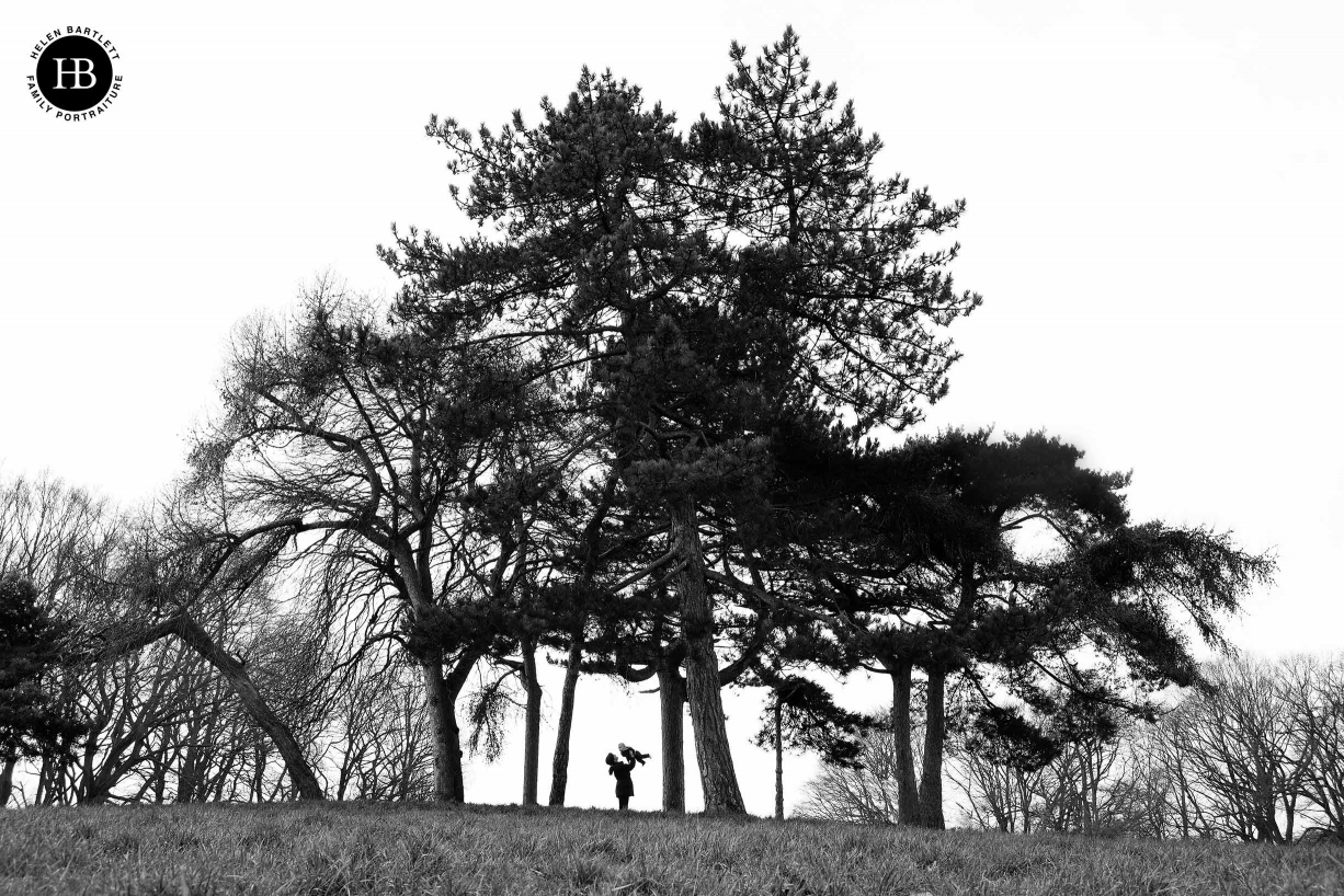 silhouette of trees on hampstead heath with mother and baby as focal point