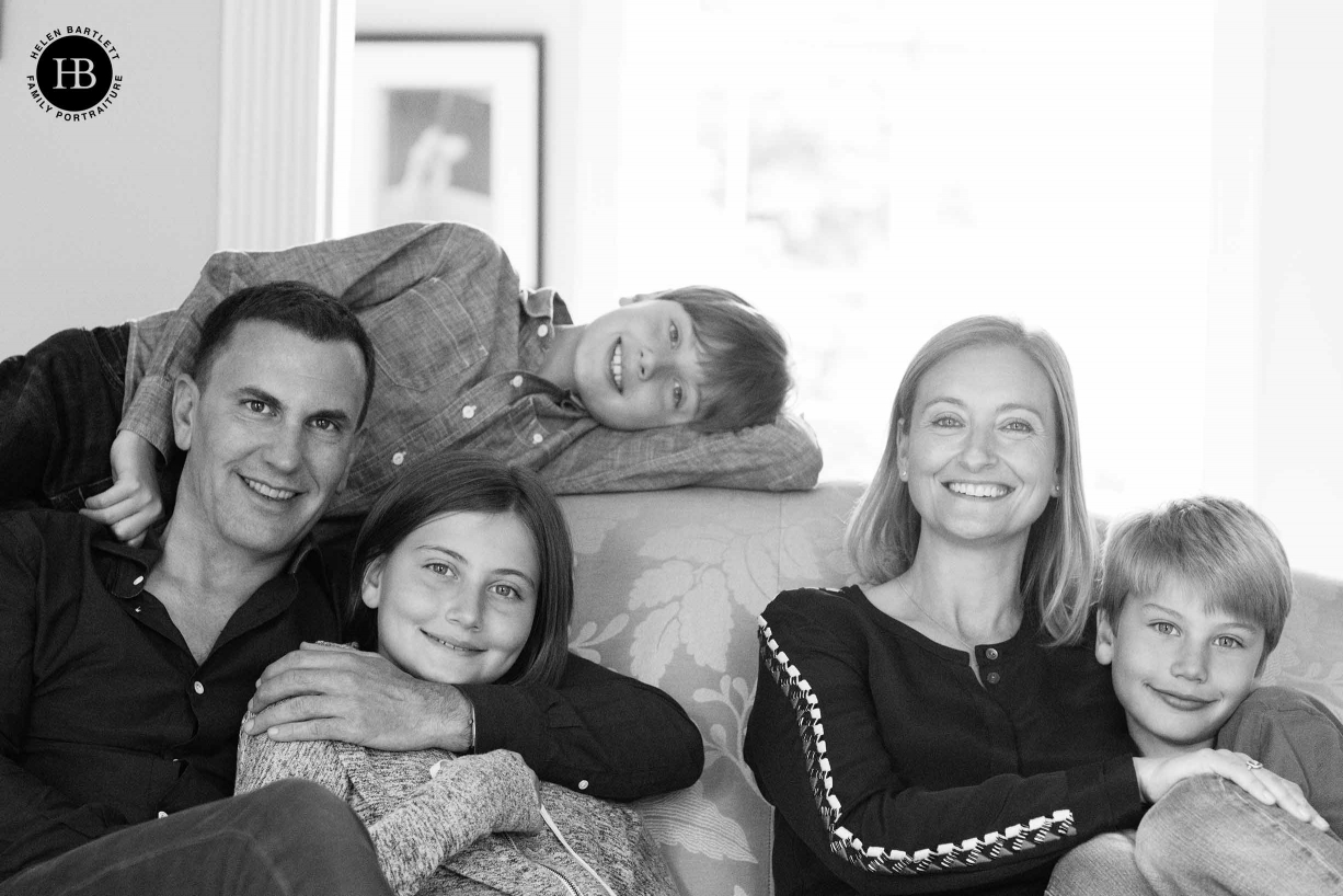 Formal family portrait of mum, dad, and three teenagers on sofa in London home