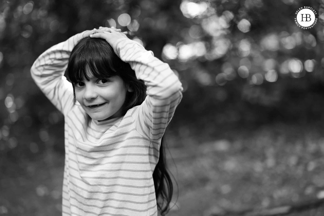 Portrait of a girl laughing up at the camera with hands on her head. Image to demonstrate lovely tones and fabulous detail in Canon EOS R5 files.