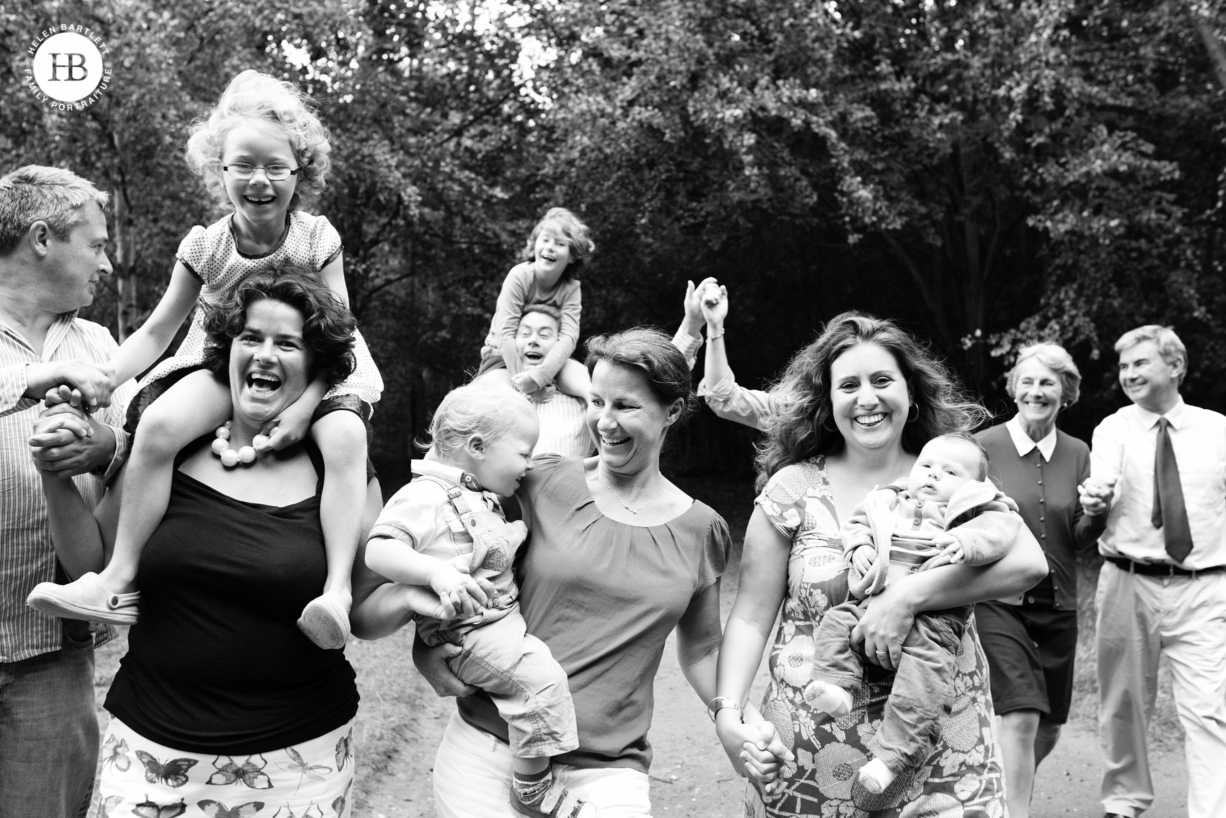 large multi-generational family photograph with everyone laughing and running towards the camera