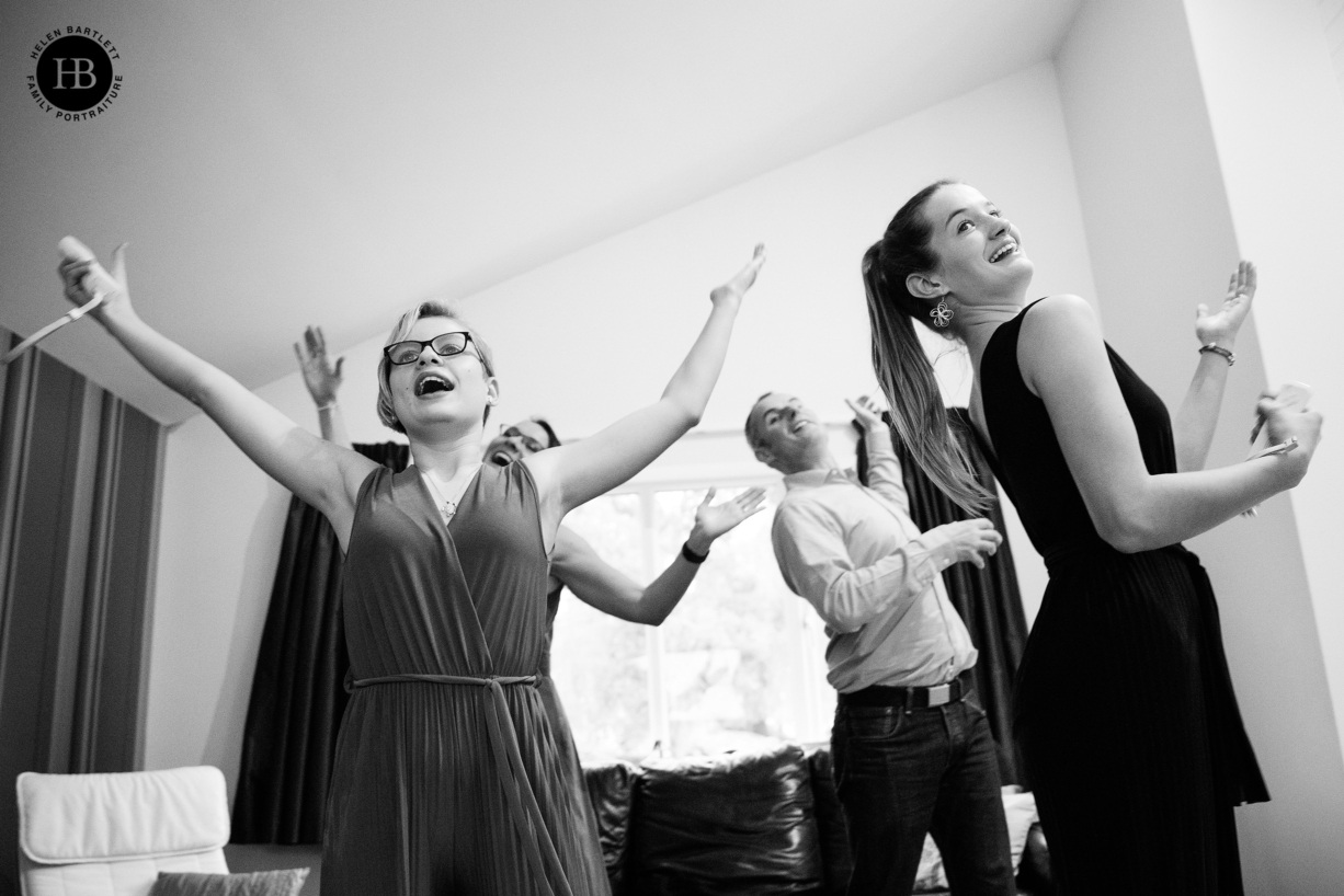 teenage girls play wii dance while wearing formal dresses on family photo shoot