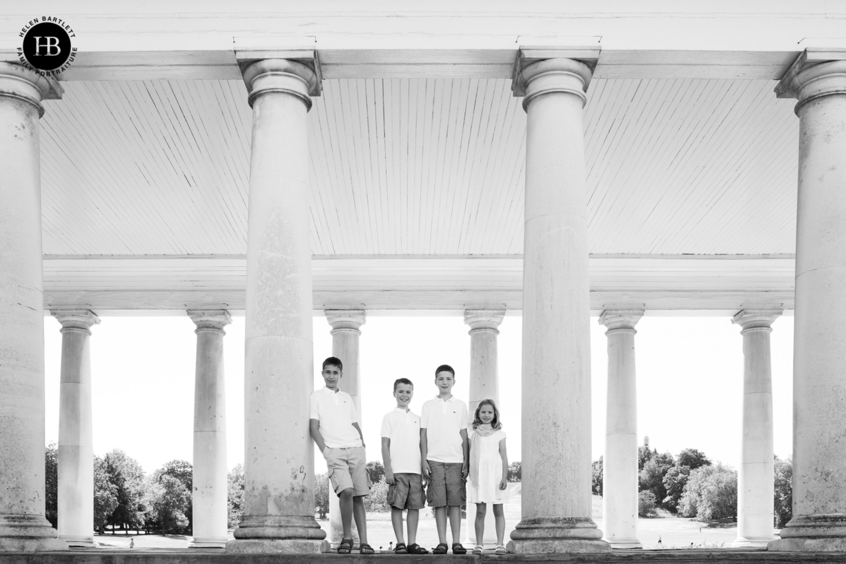 four children in matching white outfits formally pose on a family photo shoot in London