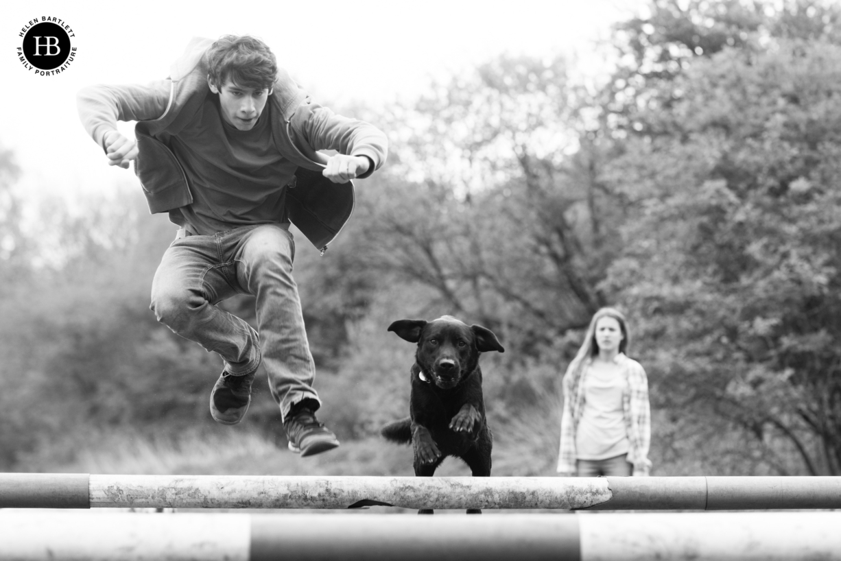 teenage boy plays with dog jumping over show jumps