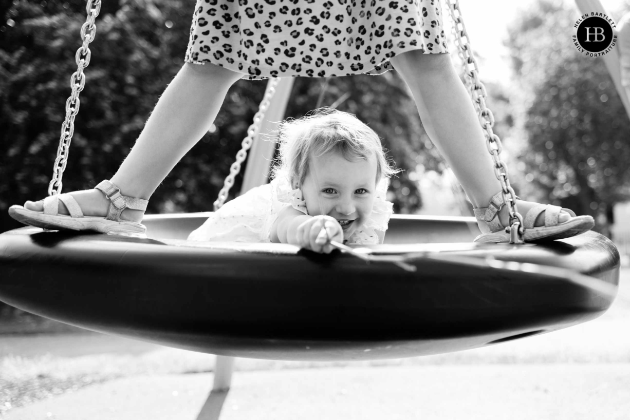 two girls play on the swings during a photo shoot of family photography in east London