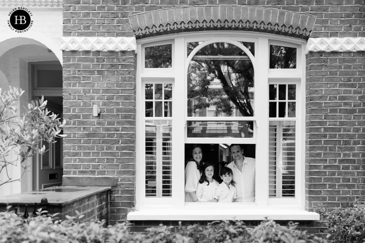 family looks out of window of their home in west London. Professional photo in black and white