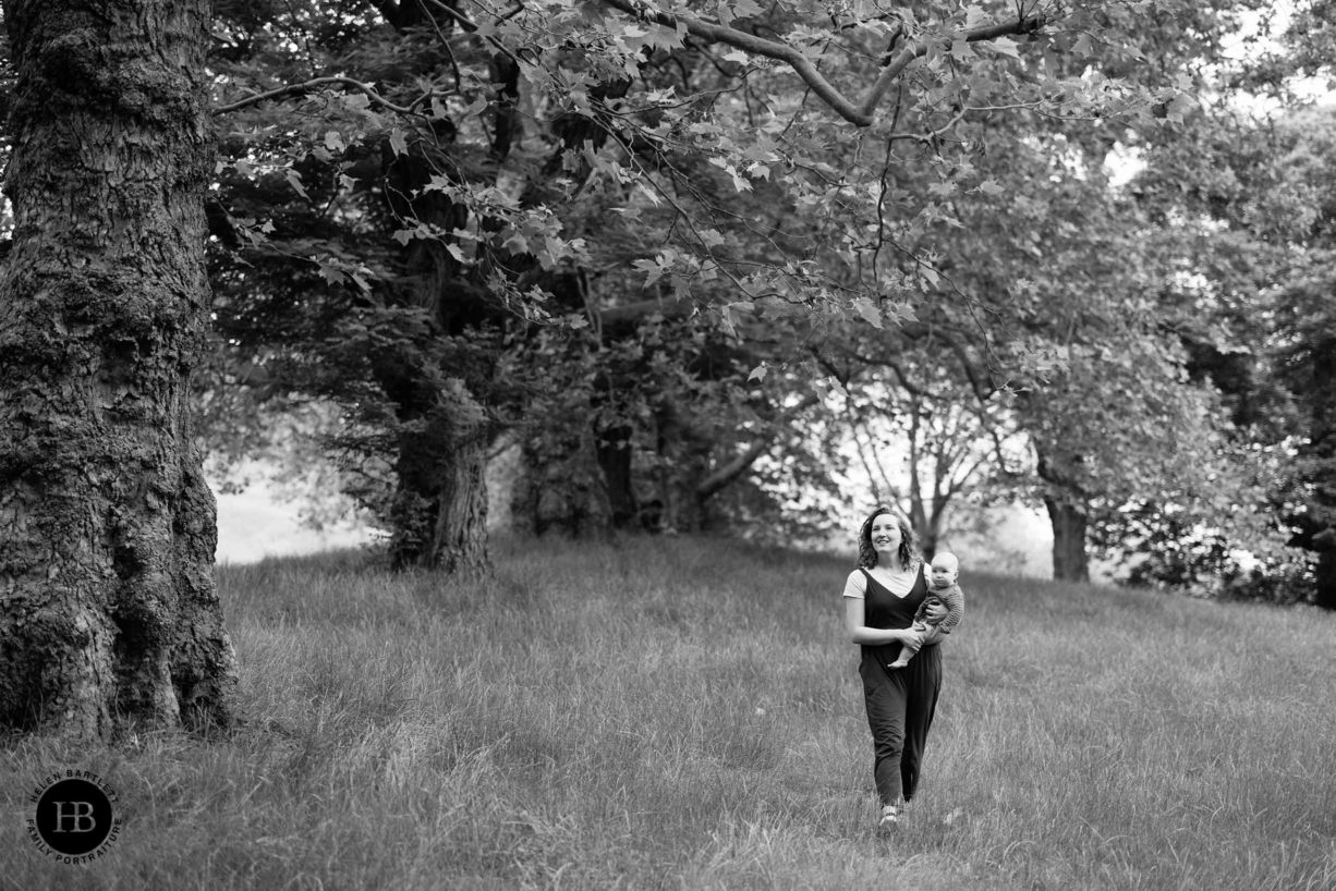 mum and baby walk through the trees during a professional family photo shoot in greenwich park