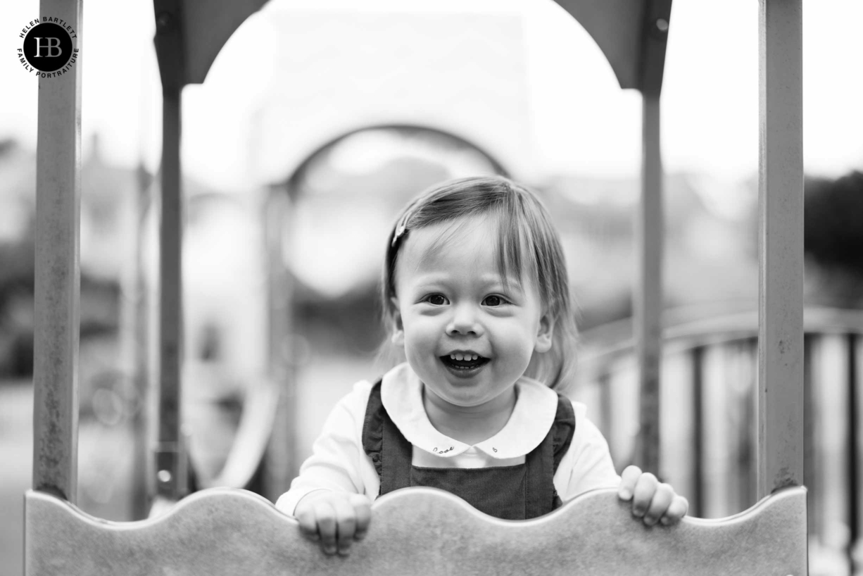 Portrait of two year old girl laughing while playing on the climbing frame