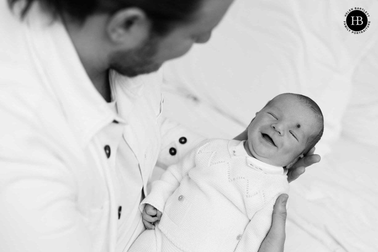 laughing newborn baby held by his dad on primrose hill newborn photography session