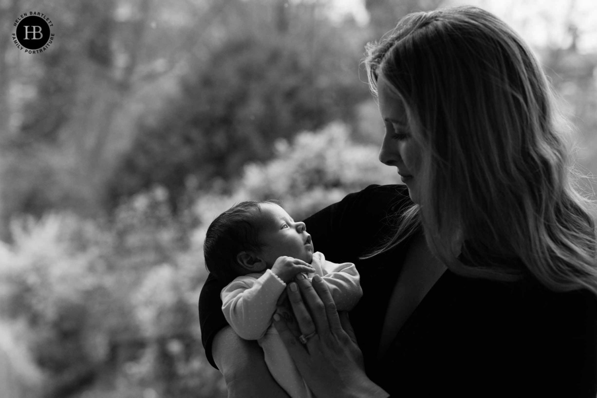 black and white backlit portrait of mum and newborn baby in front of window