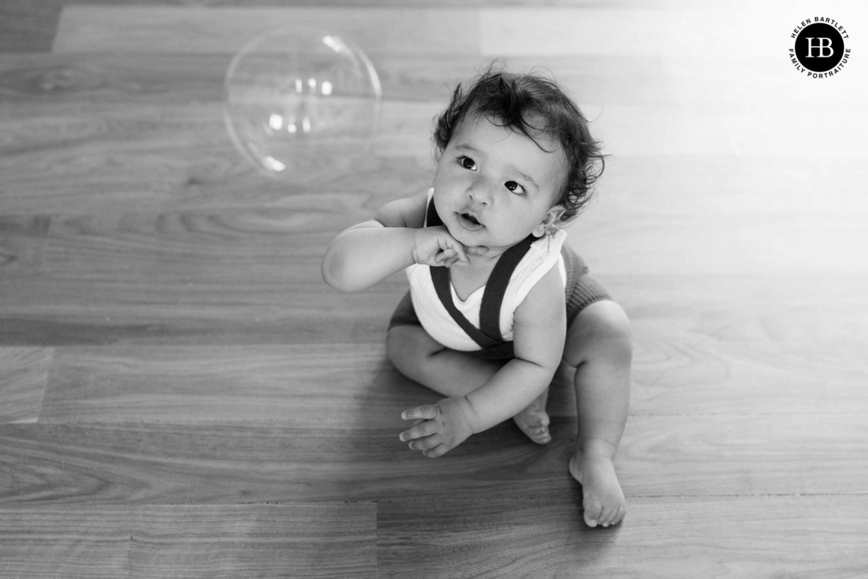 baby-looking-at-bubble-sat-wooden-floor