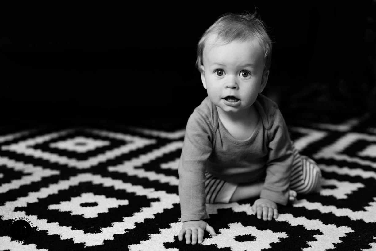 baby crawls on black and white patterned run during family photo shoot in Ealing