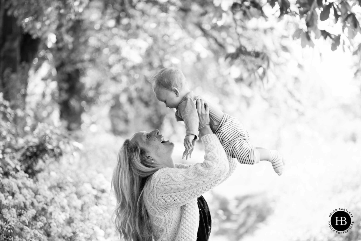 Mum lifts baby in the air during family photography session in Ealing