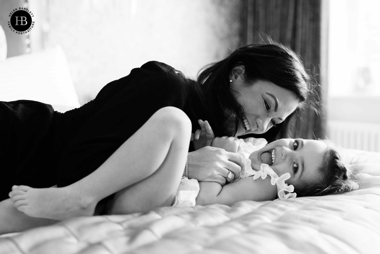 mum and daughter play on the bed during an at home family photography session in Brentwood