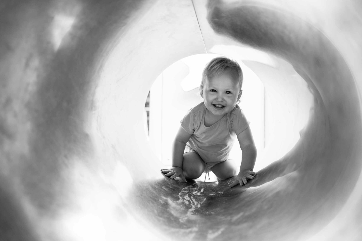 portrait of toddler in tunnel in the playground of victoria park in hackney