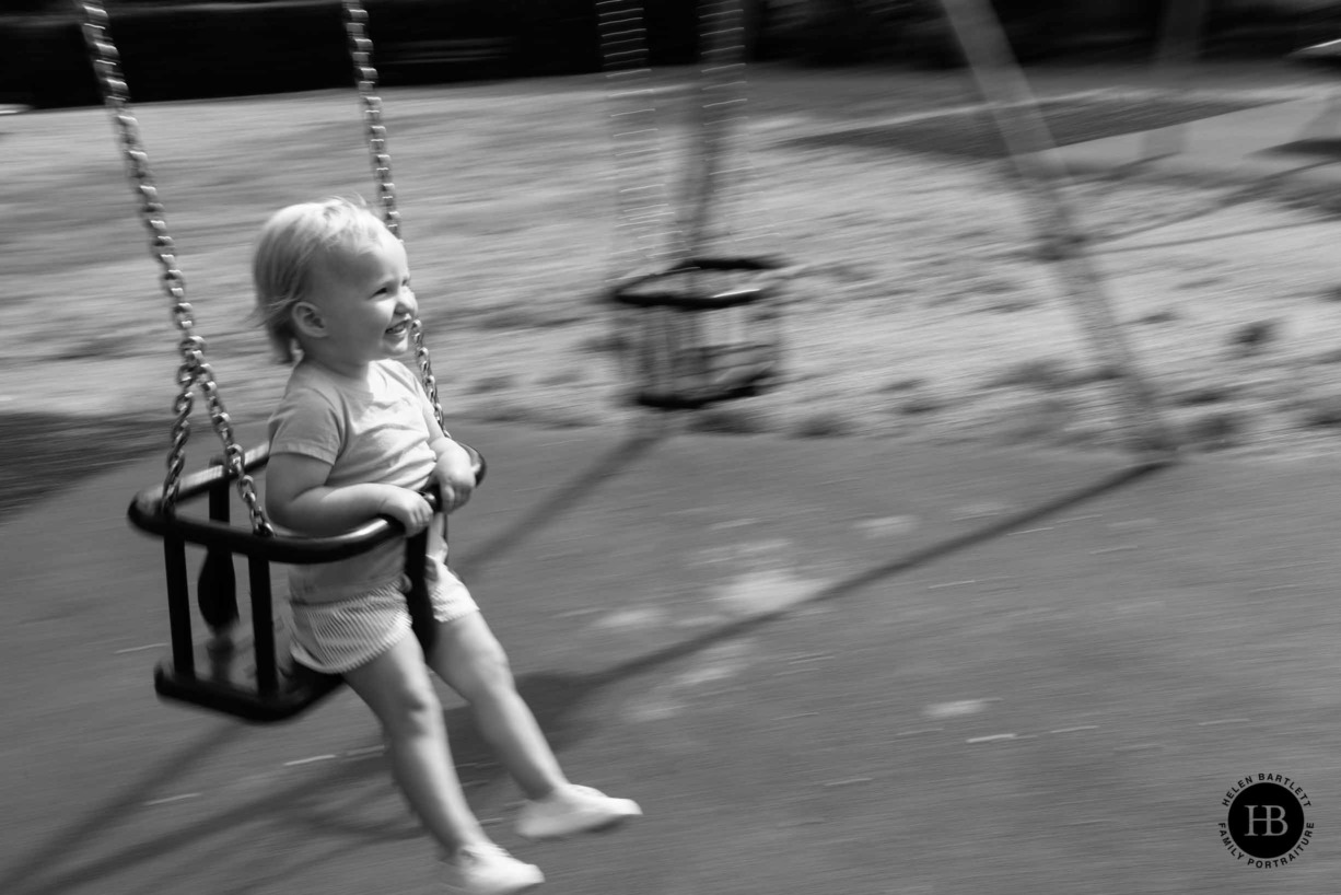 little girl plays on swings in victoria park shot with panning technique