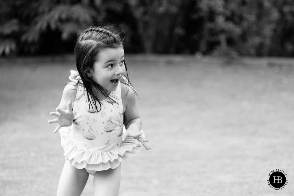 little girl excited by water spray during a family photo shoot at her home in brentwood