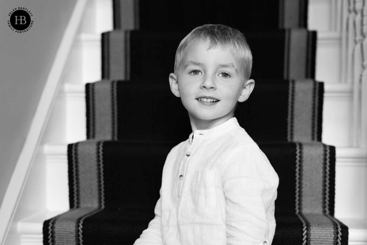 classic-black-and-white-portrait-young-boy-sitting-on-stairs-winchmore-hill-home