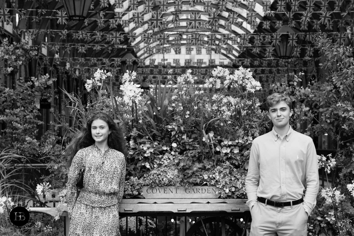 Teenage girl and boy pose in front of flower display in London's Covent Garden on a professional photo shoot