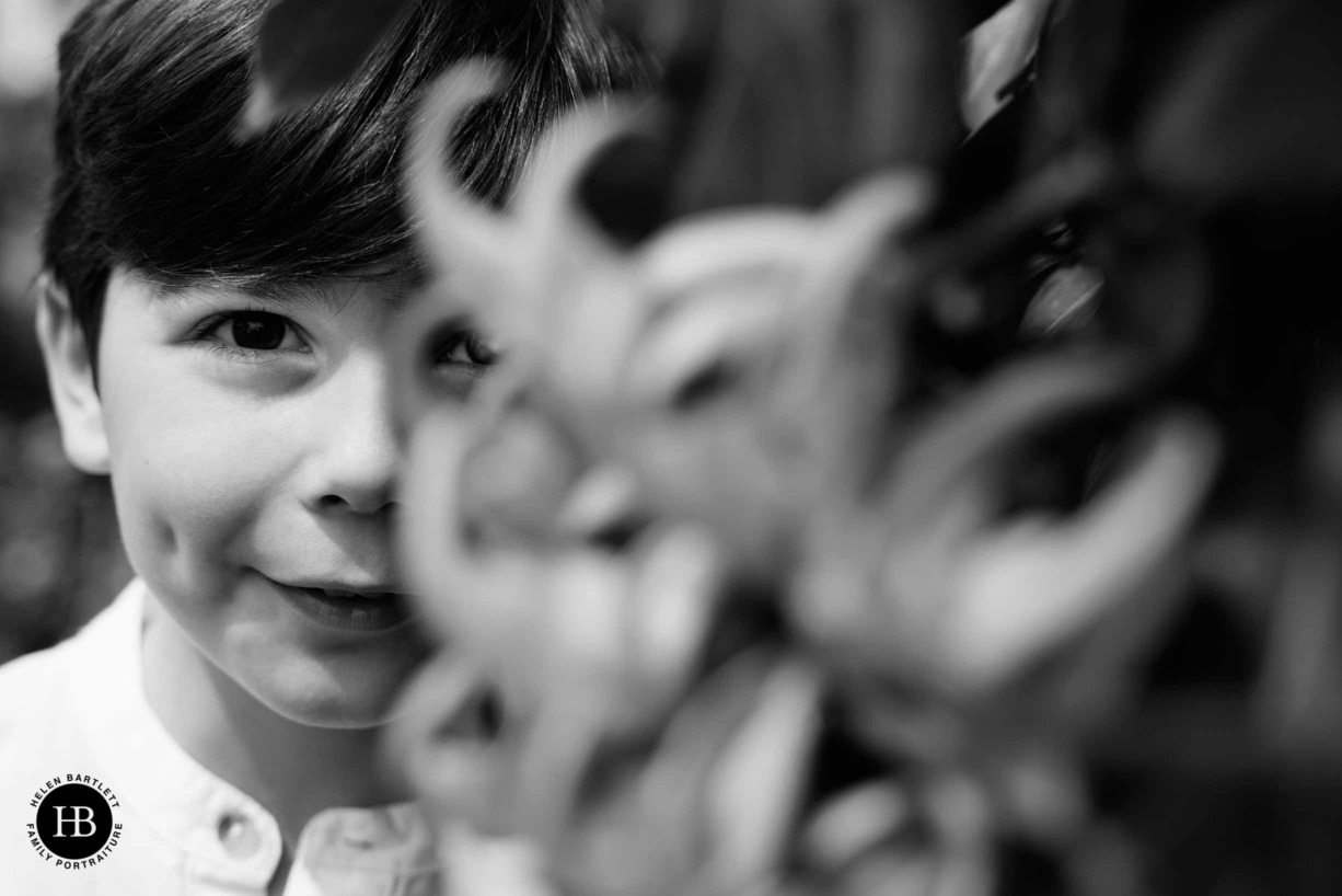 little-boy-looks-through-foliage-wisley-gardens-surrey