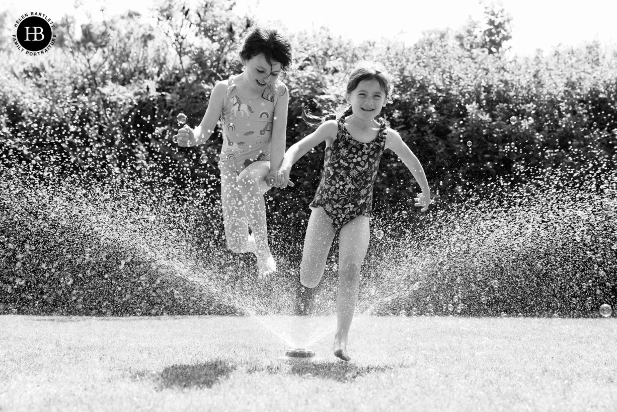 two-five-year-old-girls-leap-through-water-spray-laughing