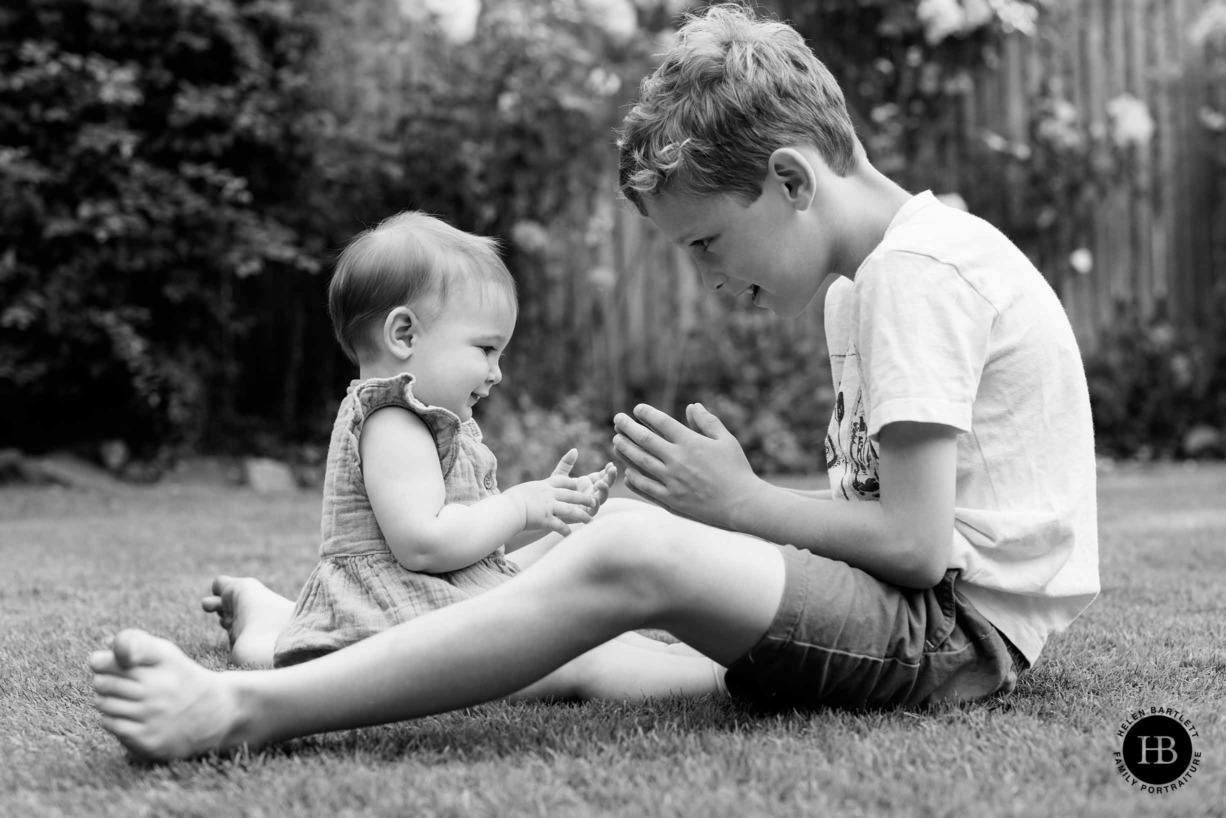 young-boy-plays-game-in-garden-with-baby-sister