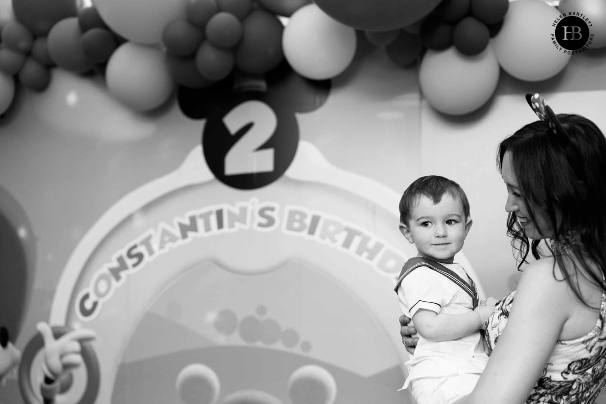 monochrome-photo-boy-and-mother-in-front-party-banner