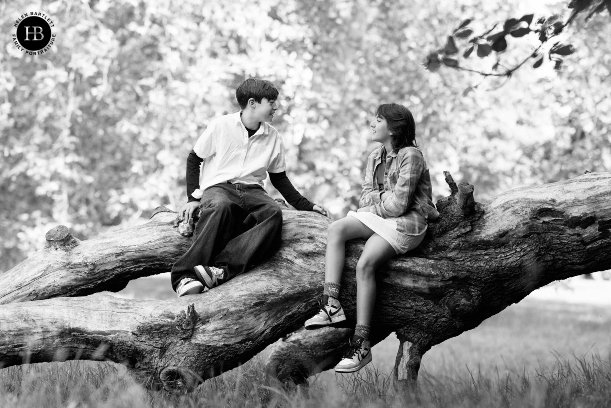 teenage-siblings-sit-on-tree-laughing